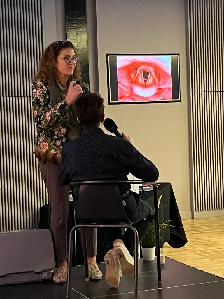 Le Dr Joëlle Huth, micro en main, explique un examen devant une assistance, lors d’une conférence
