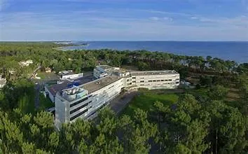Vue aérienne de l’hôpital privé Wallerstein à Arès : un bâtiment clair entouré de pins, avec la mer à l’horizon